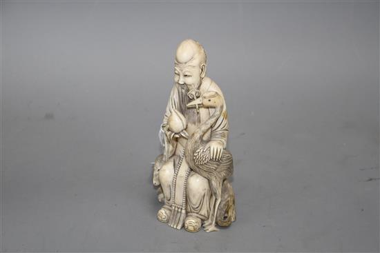 A Chinese carved ivory group of a sage holding a peach, seated beside a crane and a deer, 17cm